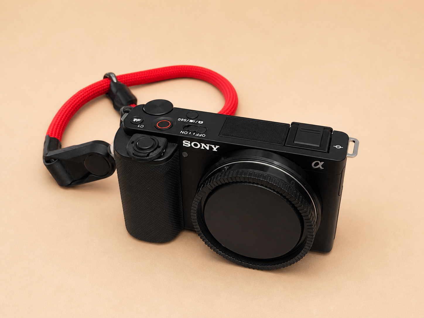 Meine schwarze Sony ZV-E10 mit roter Handschlaufe auf warmem Sandhintergrund